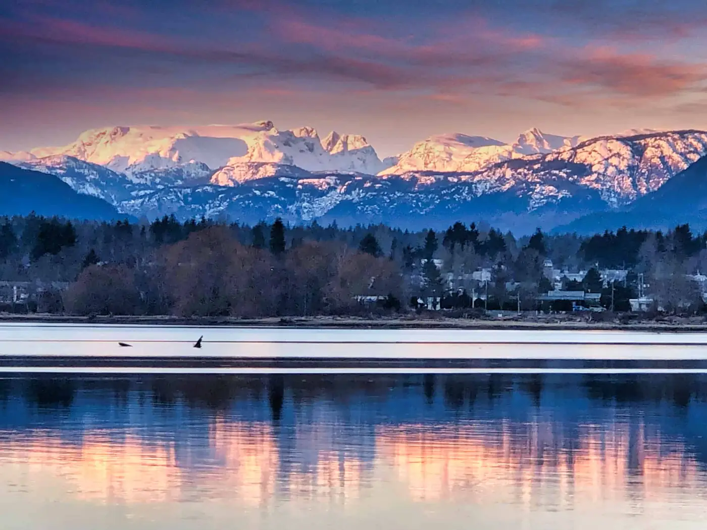 The Comox Glacier and snow-lit peaks reflected in calm water at Queneesh