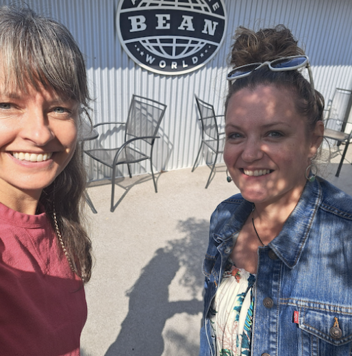 Two members grinning in front of the Bean Around The World sign