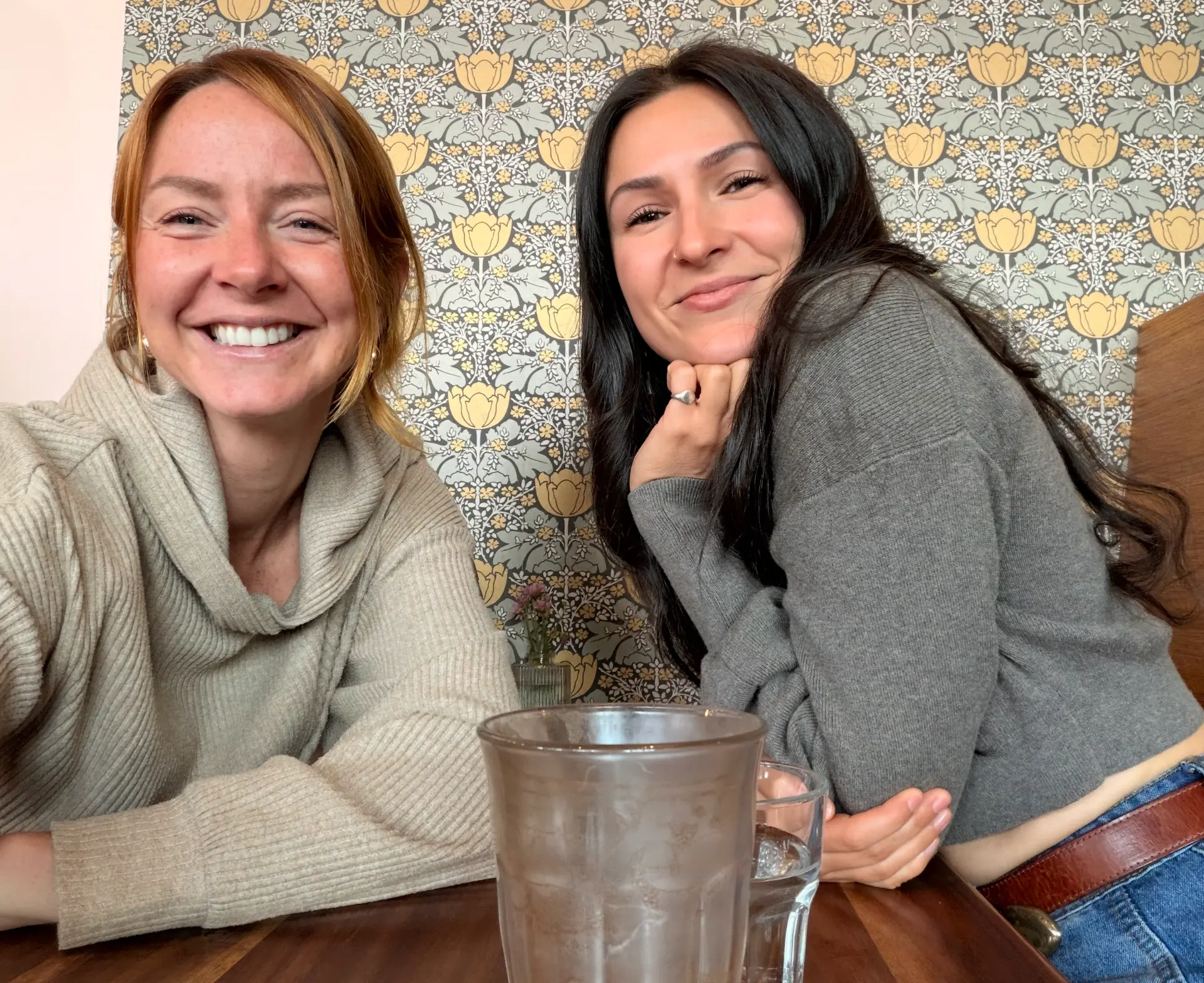 Two members in front of floral wallpaper